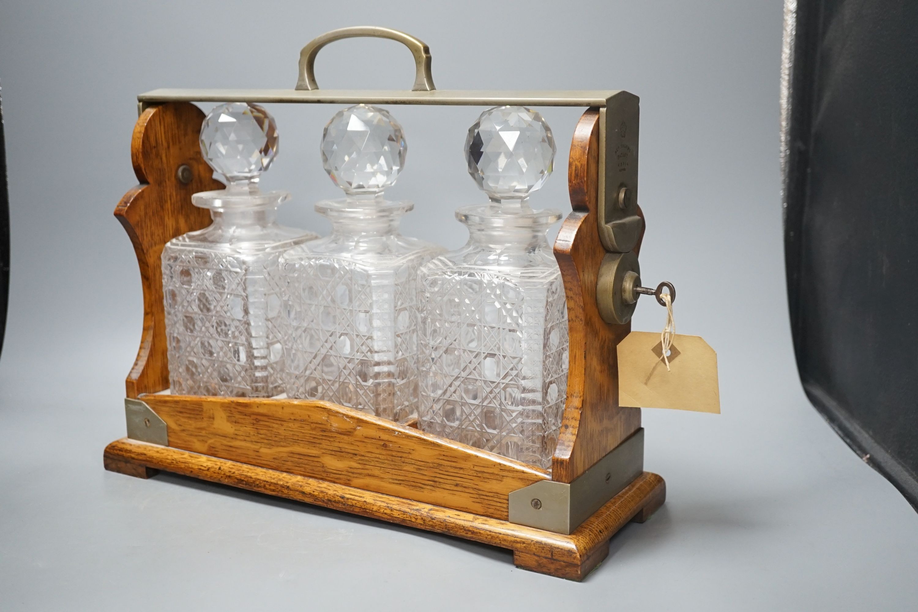 Early 20th century Betjemann's Patent oak 3 bottle tantalus, 32 cms high.